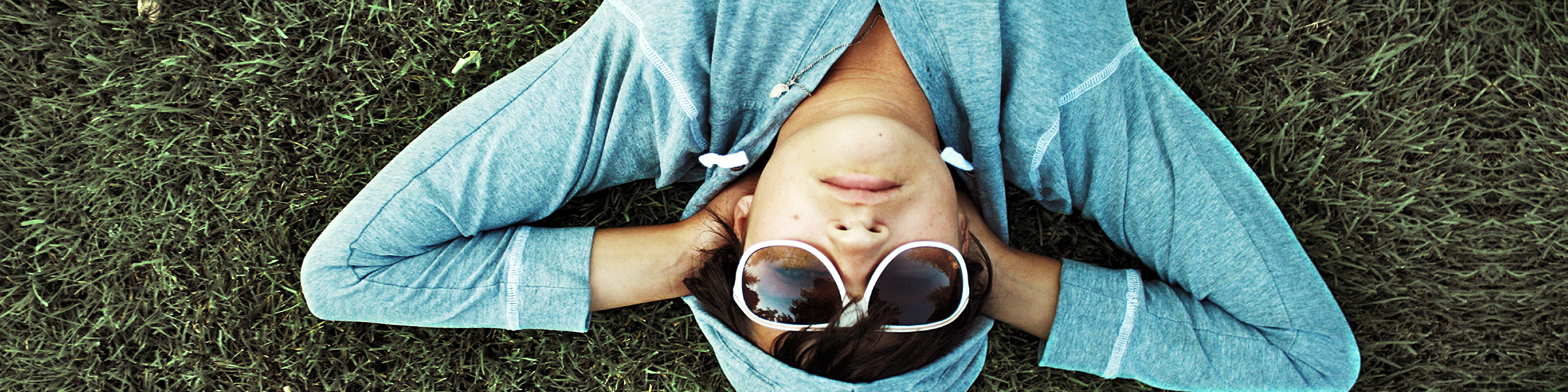 Ein junger Mensch liegt entspannt auf dem Rasen und genießt die Sonne